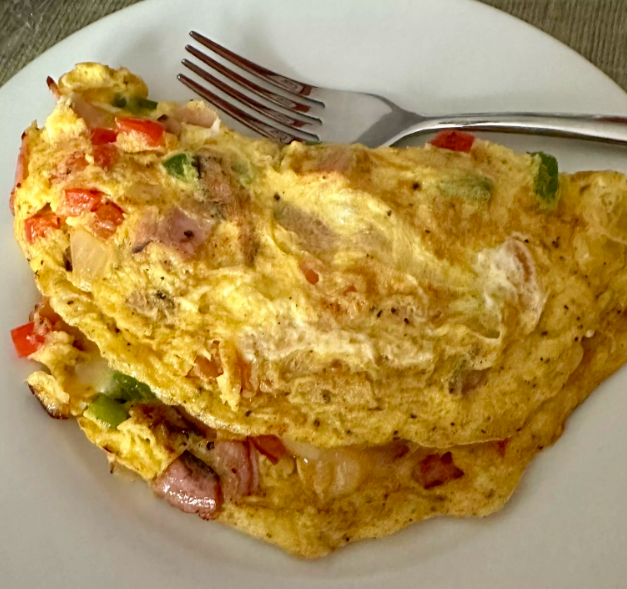 Close-up of a Denver Omelet with chicken, bell peppers, onions, and melted cheese.